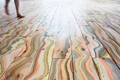 a person walking across a wooden floor covered in multicolored marble