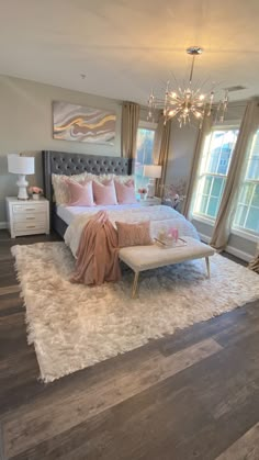 a bedroom with a large bed, chandelier and two windows in the room