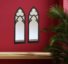 a red wall with two windows and a potted plant