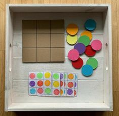 a white box with different colored circles and squares in it on top of a wooden floor