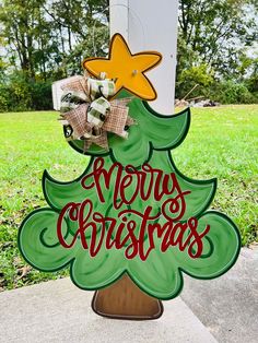 a merry christmas tree sign on the side of a mailbox in front of some grass