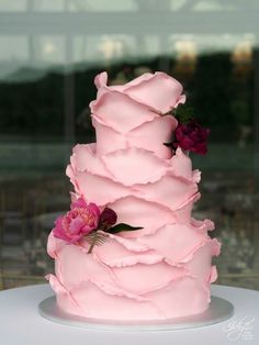 a three tiered cake with pink icing and flowers