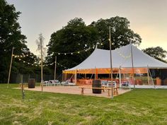 a large tent set up in the middle of a field with string lights hanging from it