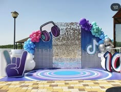 an outdoor stage set up with balloons and music notes on the wall, surrounded by disco balls