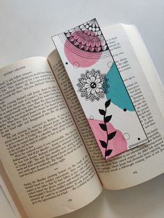 an open book with colorful designs on the pages and a tag attached to it's cover