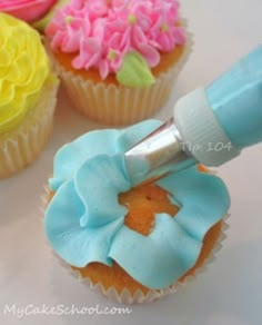 someone is painting cupcakes with icing and flowers on the frosting sheet