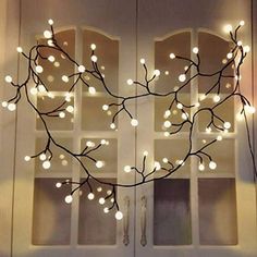 a heart shaped tree branch with white lights hanging from it's branches in front of two windows