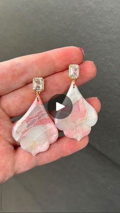 a person is holding some pink and white earrings