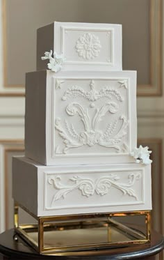 a three tiered cake with white frosting and decorative designs on the top layer