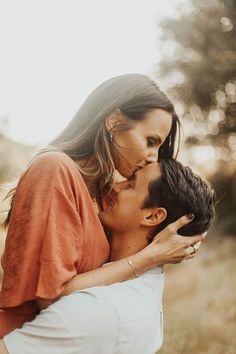 a man and woman kissing each other in the grass