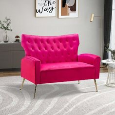 a living room with a pink couch and two pictures on the wall above it,