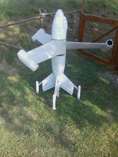 an airplane made out of plastic sitting in the grass next to a fence and gate