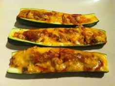 three stuffed zucchini boats sitting on top of a white counter next to each other