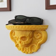 a pair of black sunglasses sitting on top of a yellow shelf next to two framed pictures