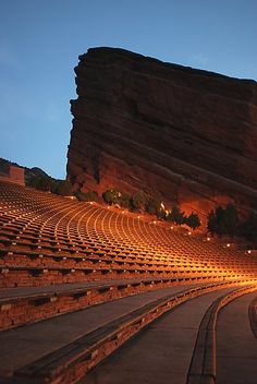 an empty auditorium with steps leading up to the stage and mountains in the background at night