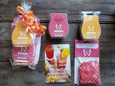 four different types of soaps in plastic bags on a wooden table with orange ribbons