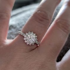 a woman's hand with a diamond ring on top of her finger, showing the center stone