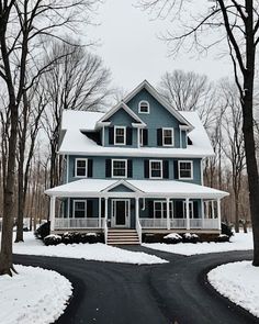 a large blue house in the middle of winter with snow on the ground and trees around it