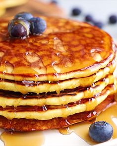 a stack of pancakes with syrup and blueberries