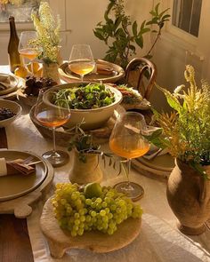 the table is set with plates, bowls and glasses of wine for two people to enjoy