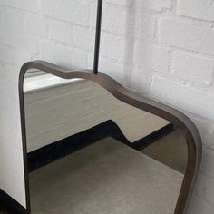 a large mirror sitting on top of a floor next to a white brick wall,