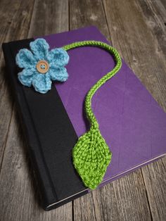 a crocheted book with a flower on it sitting on top of a wooden table