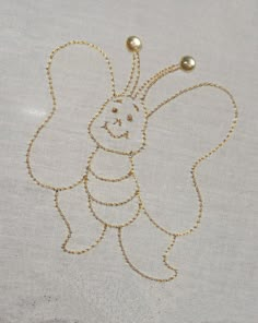 an embroidered angel ornament with two bells on it's back and gold chain