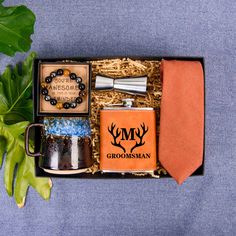 the groomsmen gift box includes two flasks, an orange tie and personal items