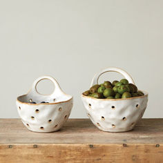 two white bowls filled with green fruit sitting on top of a wooden table next to each other