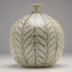 a white vase with leaves painted on it