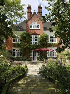 a large brick house surrounded by trees and flowers