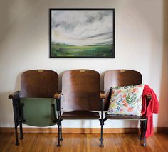 three empty seats in front of a painting on the wall