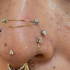 a close up of a person's nose with gold jewelry on it and piercings