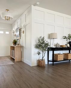 a living room with white walls and wood floors, plants on the table in front of it