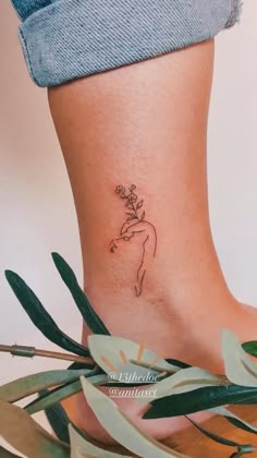 a woman's foot with a small tattoo on the side of her body and leaves surrounding it