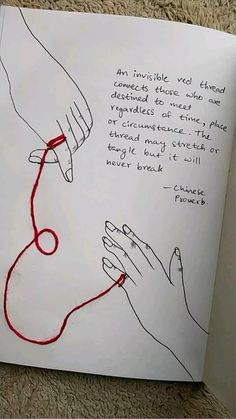 an open book with two hands holding a red string