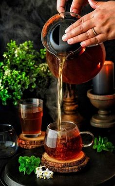 a person pouring tea into a glass cup