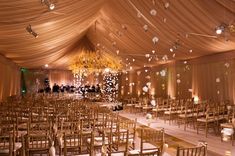 the inside of a wedding tent with chairs and chandeliers hanging from the ceiling