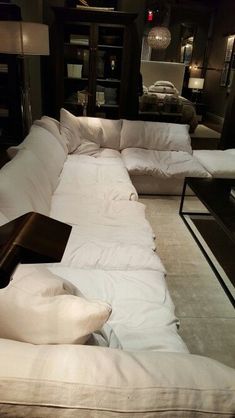 a living room filled with white couches and lots of pillows on top of them