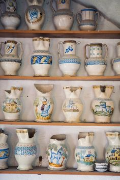 a shelf filled with lots of vases on top of wooden shelves