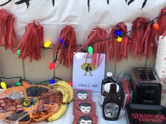 a table topped with lots of food next to a sign and string lights hanging from the ceiling