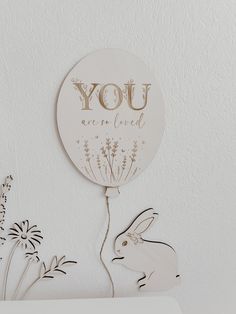 a paper cut out of a bunny holding a balloon with the words you are loved on it