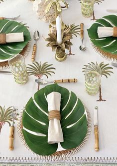 the table is set with palm leaves and place settings for two people to sit at