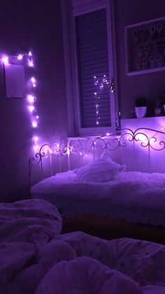 a bed with purple lights on the headboard in a room filled with white blankets