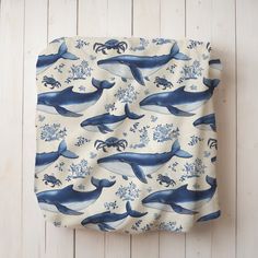 a blue and white whale print pillow on a wooden wall with an ocean themed background