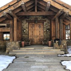 a stone house with wooden doors and steps leading up to the front door in winter