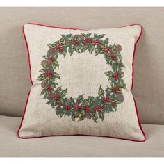 a christmas wreath pillow sitting on top of a couch next to a white sofa cushion