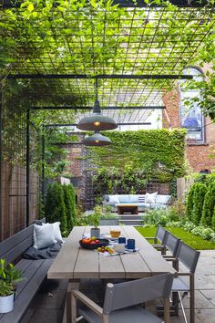 an outdoor dining area with wooden table and benches under a pergolated trellis