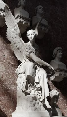 black and white photograph of an angel sitting on a stone statue with other statues in the background