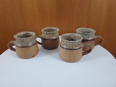 four coffee mugs sitting on top of a white table